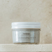 Oak & Sage Exfoliating Balm in glass jar, formulated with fine pumice, tallow, and calendula to gently remove dead skin and support skin barrier health.