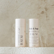 Oak & Sage Unscented Lip Balm duo with eco-friendly paper tubes, featuring clean, natural ingredients like tallow, jojoba oil, vanilla, honey, and beeswax, styled against a neutral stone background.