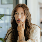 Woman applying Oak & Sage natural, non-toxic tallow-based lip balm indoors, highlighting everyday hydration and clean skincare ritual.