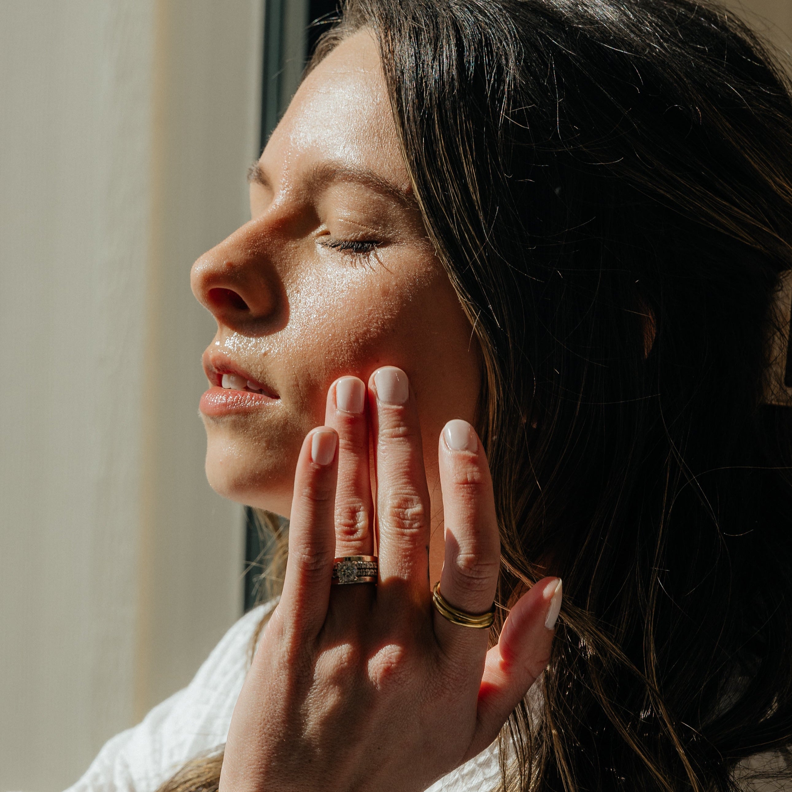 Woman gently touching dewy, hydrated skin after applying Oak & Sage hydrosol, showcasing radiant glow and natural skincare results.