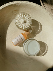 Top-down view of Oak & Sage Complete Skincare Set textures: whipped Youthful Cream, radiant golden serum, and smooth Cleansing Balm in sunlight on a ceramic dish.