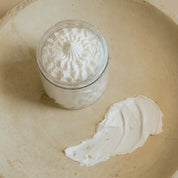 Open jar of Oak & Sage Everywhere Cream showing whipped, airy texture with a smooth swipe of nourishing tallow body butter on a neutral ceramic plate.