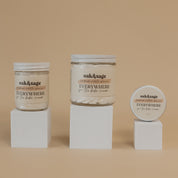 Oak & Sage Everywhere Cream in For The Babe scent displayed in three sizes—large jar, medium jar, and travel tin—on minimalist white pedestals against a warm beige background