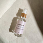 Oak & Sage Rose Organic Hydrosol bottle with bamboo spray top photographed in natural light on a textured neutral background.