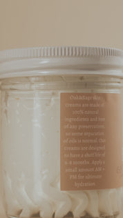 Oak & Sage Everywhere Cream in Warm Vanilla scent, shown in a slow-motion 360-degree spin with the whipped tallow cream visible through a clear glass jar and the handcrafted label facing the camera.